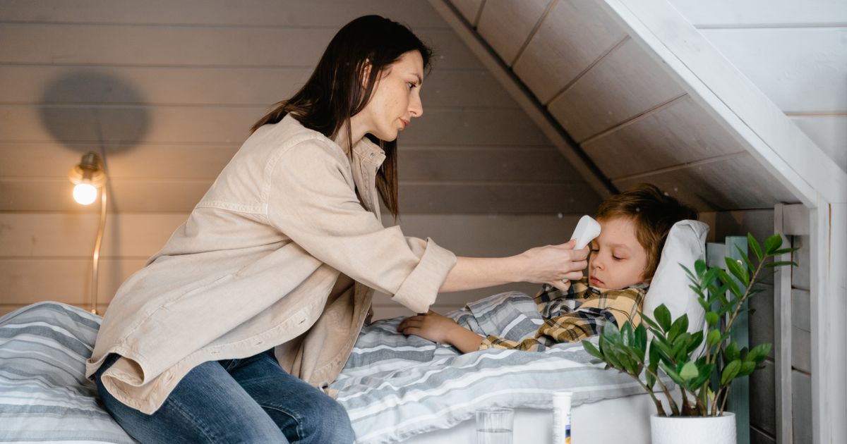 Une maman prenant la température de son enfant malade au lit