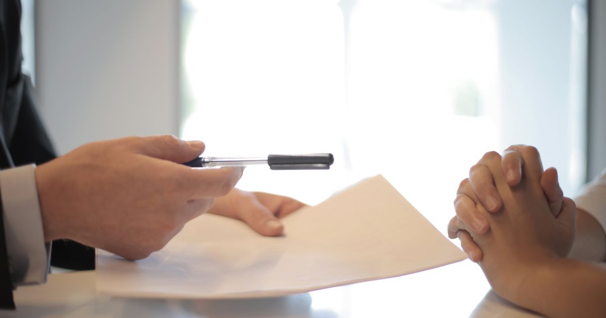 Un stylo et une feuille tendus pour être signés